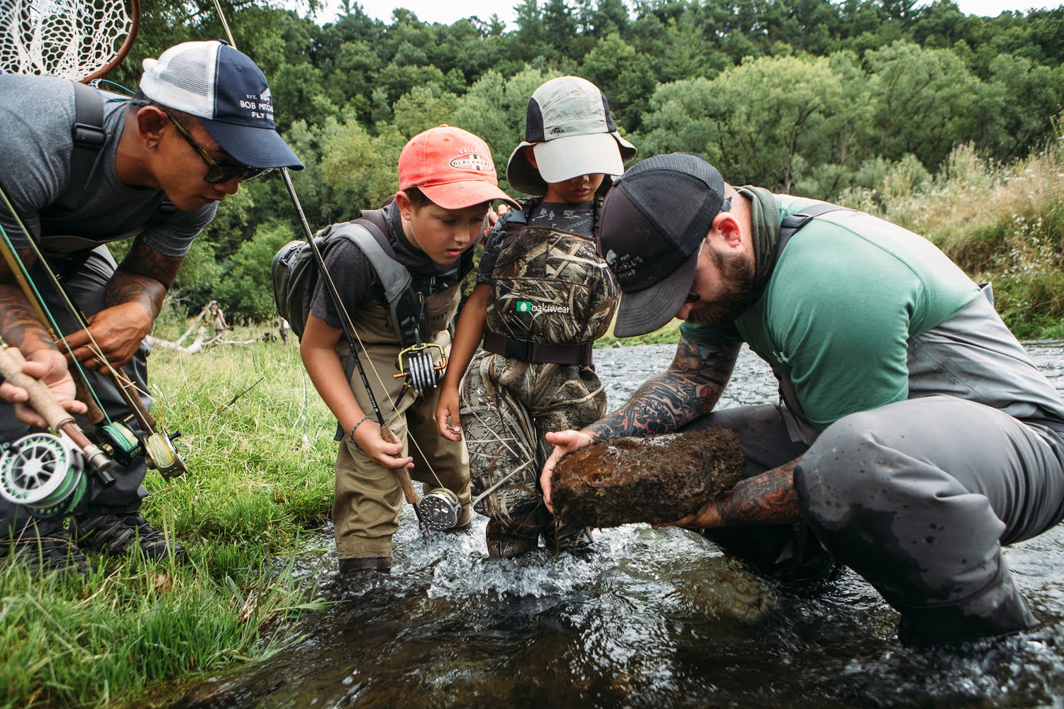 Image of Bret showing the under-side of a rock to 1 adult and 2 children clients