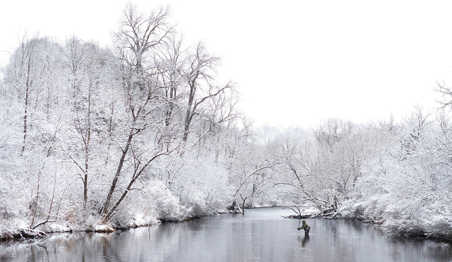 Image of Bret fly fishing in a river amongst snowy trees